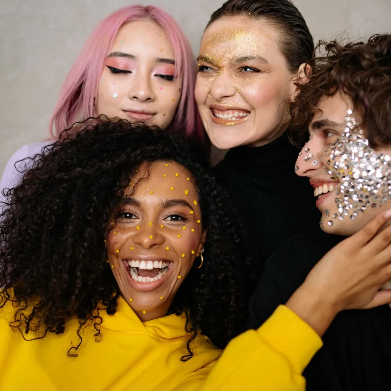 Renkli glitter makyajıyla poz veren neşeli bir arkadaş grubu